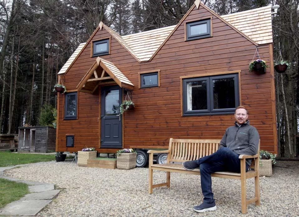 Chris devant sa maison écologique