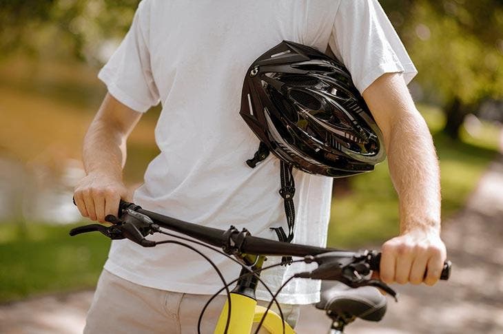 Cycliste tenant son casque et son vélo