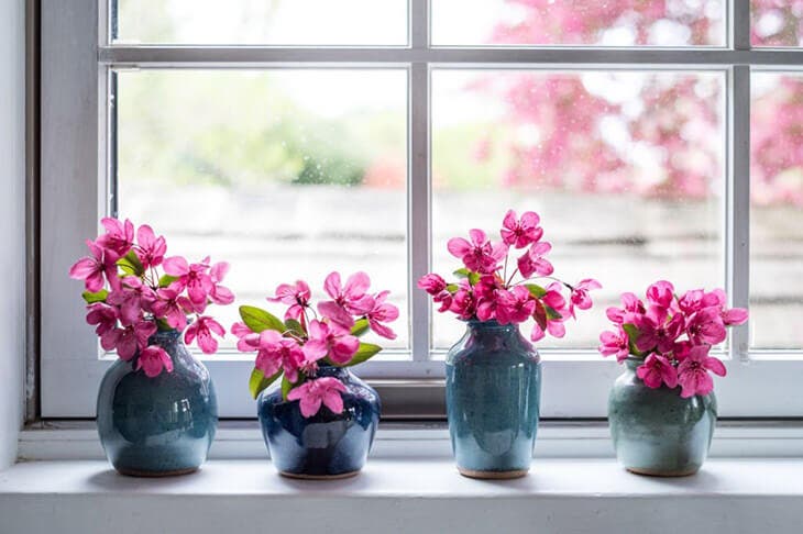 Des fleurs placées dans un vase près de la fenêtre 