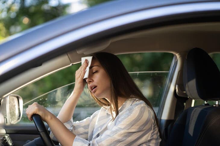 Femme endurant la chaleur au volant de sa voiture 