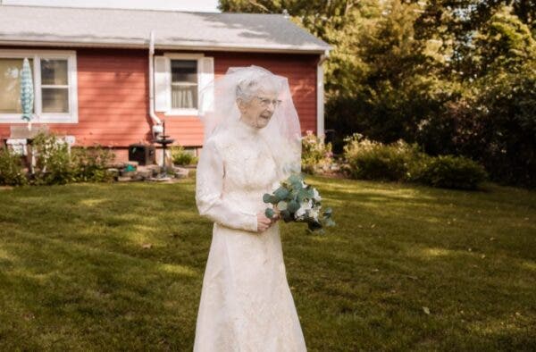 Frankie King en robe de mariée blanche fleurs aux mains