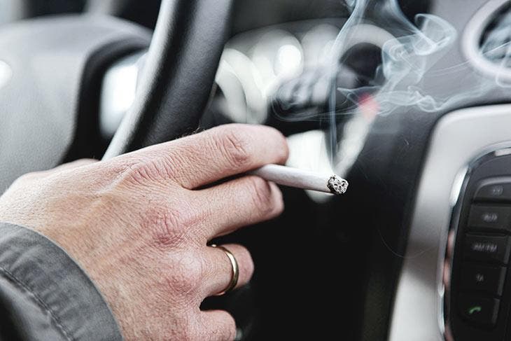 Homme qui fume à l’intérieur d’une voiture