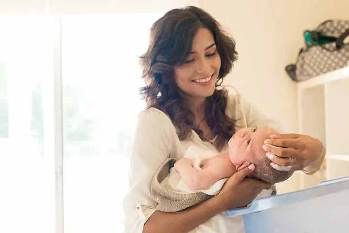 Jeune maman en train de laver les cheveux de son bébé