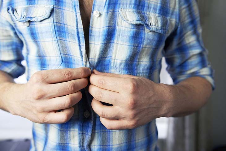 Un homme ferme les boutons de sa chemise 