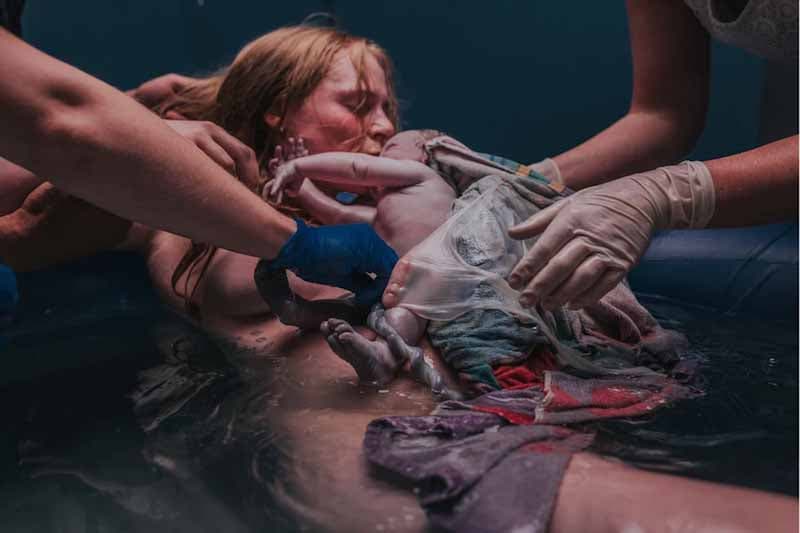 Une femme qui donne naissance à un enfant dans un bain d’eau chaude