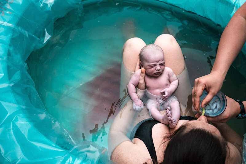 Une mère en train de boire en tenant son bébé