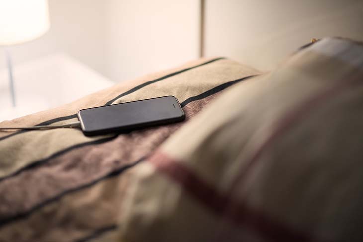 Téléphone en charge posé sur le lit – source : spm